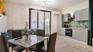 A modern kitchen with grey cabinets, a built-in oven, and a window with decorative curtains. - Apartment 'Casa Cattaleya' with Shared Pool, Private Terrace and Shared Garden (Desenzano del Garda)