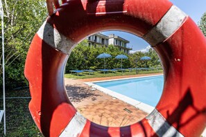 Une bouée de sauvetage, avec en arrière-plan une piscine, des parasols et un bâtiment.