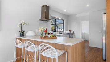 A modern kitchen with a central island, bar stools, a window, and a built-in oven.