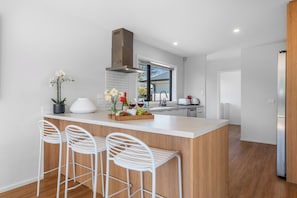 A modern kitchen with a central island, bar stools, a window, and a built-in oven.