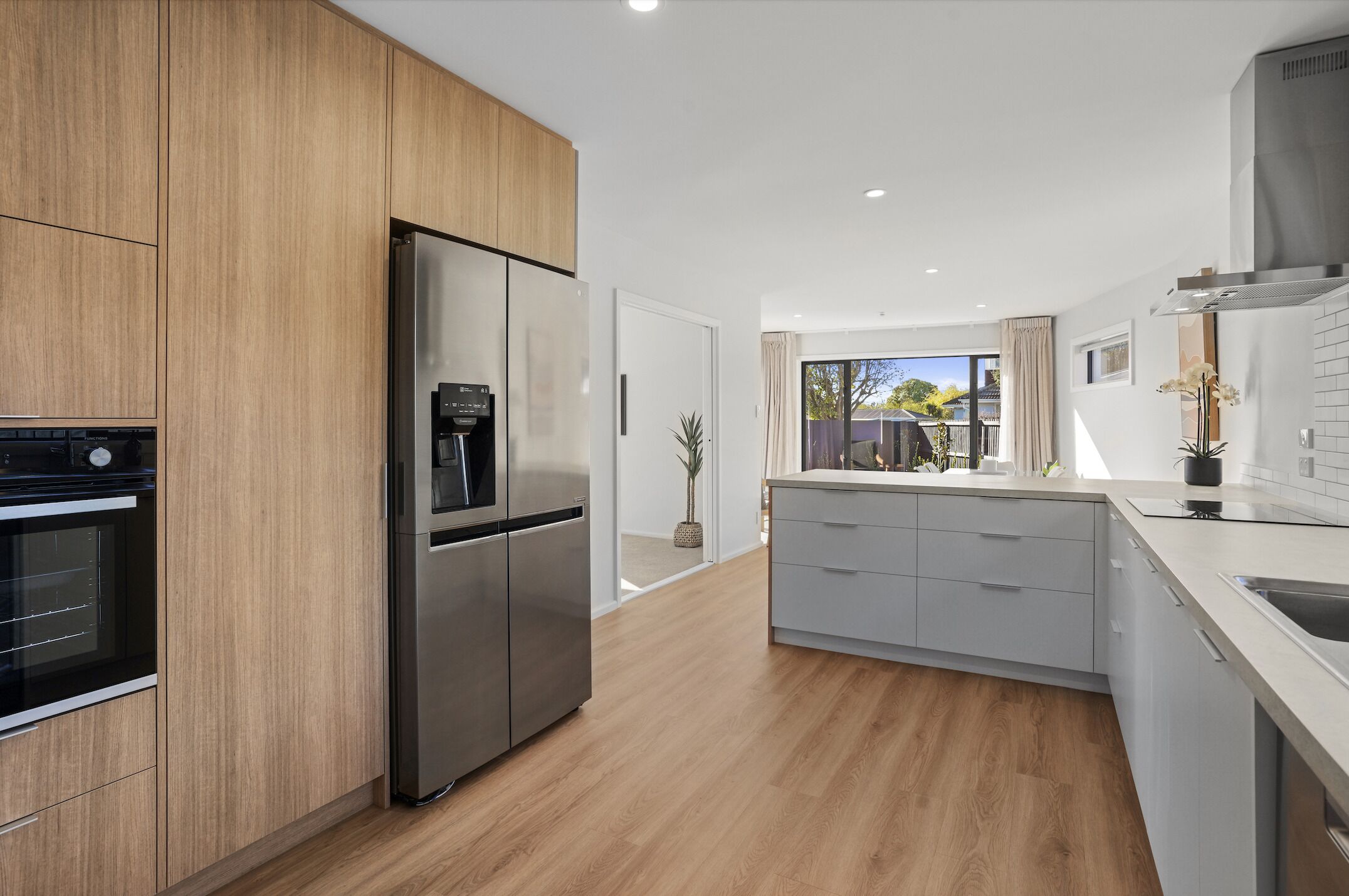 A modern kitchen with wooden cabinets, a stainless steel refrigerator, and a built-in oven.