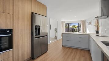 A modern kitchen with wooden cabinets, a stainless steel refrigerator, and a built-in oven.