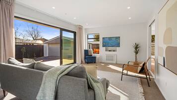 A modern living room with a grey sofa, a small table, and a TV on the wall.