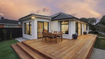 A modern house with a deck, large windows, and a well-maintained lawn.