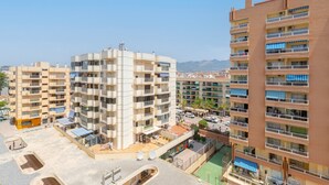 A multi-story residential building with balconies, a rooftop terrace, and a view of the surrounding area.