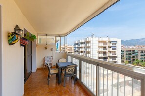 Un balcó amb una taula i cadires, una planta en test i vista d'edificis.