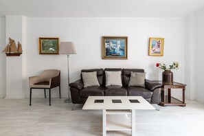 A modern living room with a leather sofa, a white coffee table, and a side table with a vase.