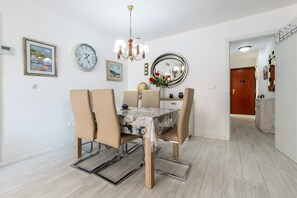 Un espace repas comprenant une table, des chaises, un lustre et des éléments de décoration murale, notamment des horloges et un miroir.