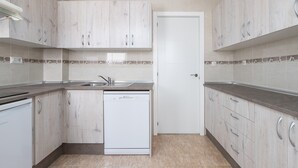 A modern kitchen with light wood cabinets, a dishwasher, and a tiled backsplash.