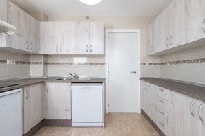 A modern kitchen with light wood cabinets, a dishwasher, and a tiled backsplash.