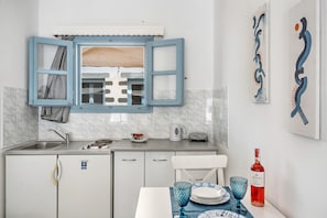 A compact kitchen with a window, sink, and a table set with plates and a wine bottle.