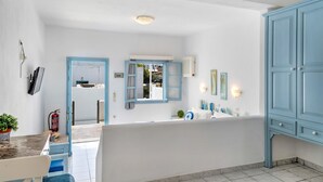 A modern hotel room with a white and blue color scheme, a large window, a bathtub, and a blue wardrobe.