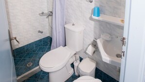 Un baño con ducha, inodoro, lavabo y un armario.