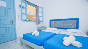 Una habitación con dos camas, una ventana con vistas, una puerta azul y un cabecero azul.