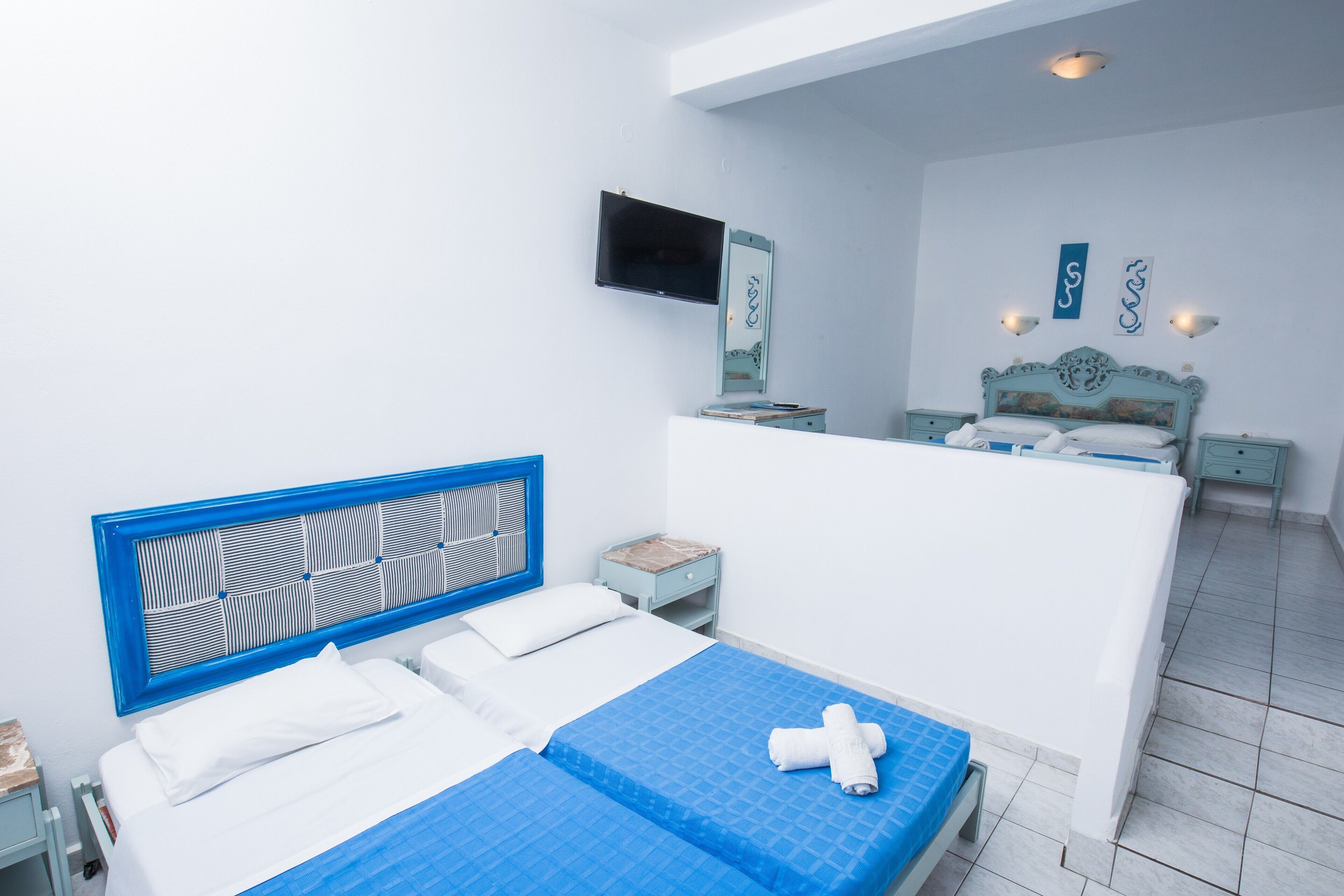 Une chambre d’hôtel avec un lit, un téléviseur fixé au mur, une petite table et une table de chevet.