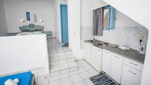 Una habitación de hotel compacta con kitchenette, una cama con cabecero y un baño con ducha.