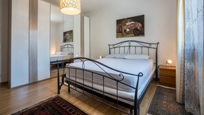 Une chambre à coucher avec un lit, une table de chevet, une lampe et un grand miroir.