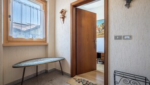 Un couloir avec une porte en bois, une petite table, un élément décoratif mural et un paillasson.