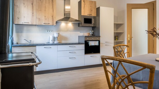 Une cuisine moderne avec des meubles en bois, un four à micro-ondes encastré et une cuisinière.