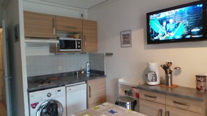 Cocina compacta con lavadora, microondas, fregadero y cafetera.