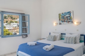 Habitació d'hotel amb un llit, un quadre a la paret i una finestra que mostra edificis.