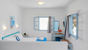 Une pièce comprenant un lit, un bureau, une chaise, une fenêtre avec des rideaux, un luminaire fixé au mur et une petite plante.