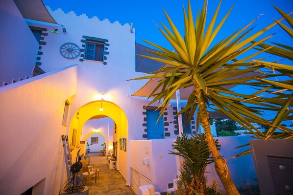 A narrow pathway leading to a building with a distinctive blue door and a large wheel-like window.