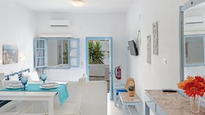 A hotel room with a dining area, a bed, a bathroom, and a view of the outside. - Apartment In A Hotel 'Pico Bello Patmos 14' with Mountain View, Wi-Fi and Air Conditioning (Patmos)