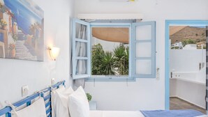 A bedroom with a bed, a window with an open shutter, a wall-mounted light, and a painting. - Apartment In A Hotel 'Pico Bello Patmos 14' with Mountain View, Wi-Fi and Air Conditioning (Patmos)
