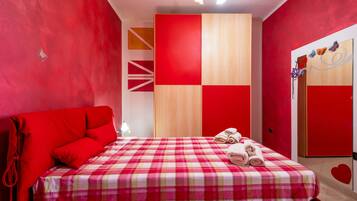 Une chambre d’hôtel avec une couvre-lit à carreaux rouges et blancs, un canapé rouge et un mur recouvert de panneaux de bois.