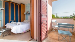 Une chambre avec un lit, une chaise, une table et un balcon offrant une vue.