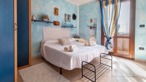 Une chambre à coucher avec un lit, une table de chevet, un miroir et une fenêtre avec des rideaux.