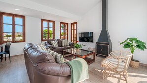 A modern living room with a leather sofa, a coffee table, a TV, and a fireplace. - Holiday Home 'Ca Na Luisa' with Sea View, Wi-Fi and Air Conditioning (Palmanova)