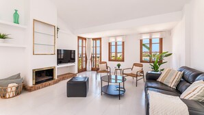 A spacious living room with a fireplace, a black leather sofa, a round coffee table, and a television. - Holiday Home 'Ca Na Luisa' with Sea View, Wi-Fi and Air Conditioning (Palmanova)