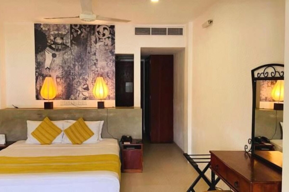 Una habitación de hotel con una cama, una mesita de noche, una lámpara y un cuadro en la pared.