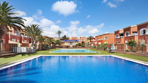 A swimming pool with a clear blue sky, palm trees, and a building labeled 'Las Dunas' in the background. - Vacation Home 'Little Dunes' with Shared Pool, Terrace & Wi-Fi (Corralejo)