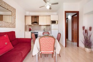 A compact living space with a dining area, kitchenette, and a red sofa.