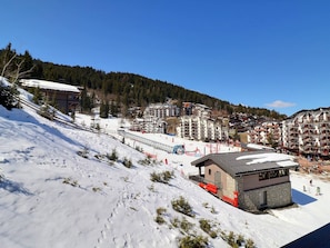 Une station de ski comprenant plusieurs bâtiments, un télésiège et une piste enneigée.