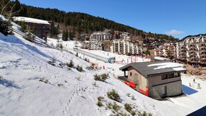Een skigebied met meerdere gebouwen, een skilift en een besneeuwde piste.