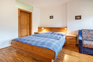 A bedroom with a wooden bed, bedside tables, a chair, and a wooden wardrobe.
