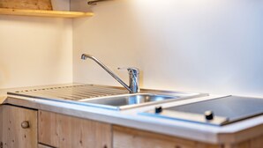 Eine Küche mit Spüle aus Edelstahl, Holzschränken und Arbeitsplatte aus Holz.