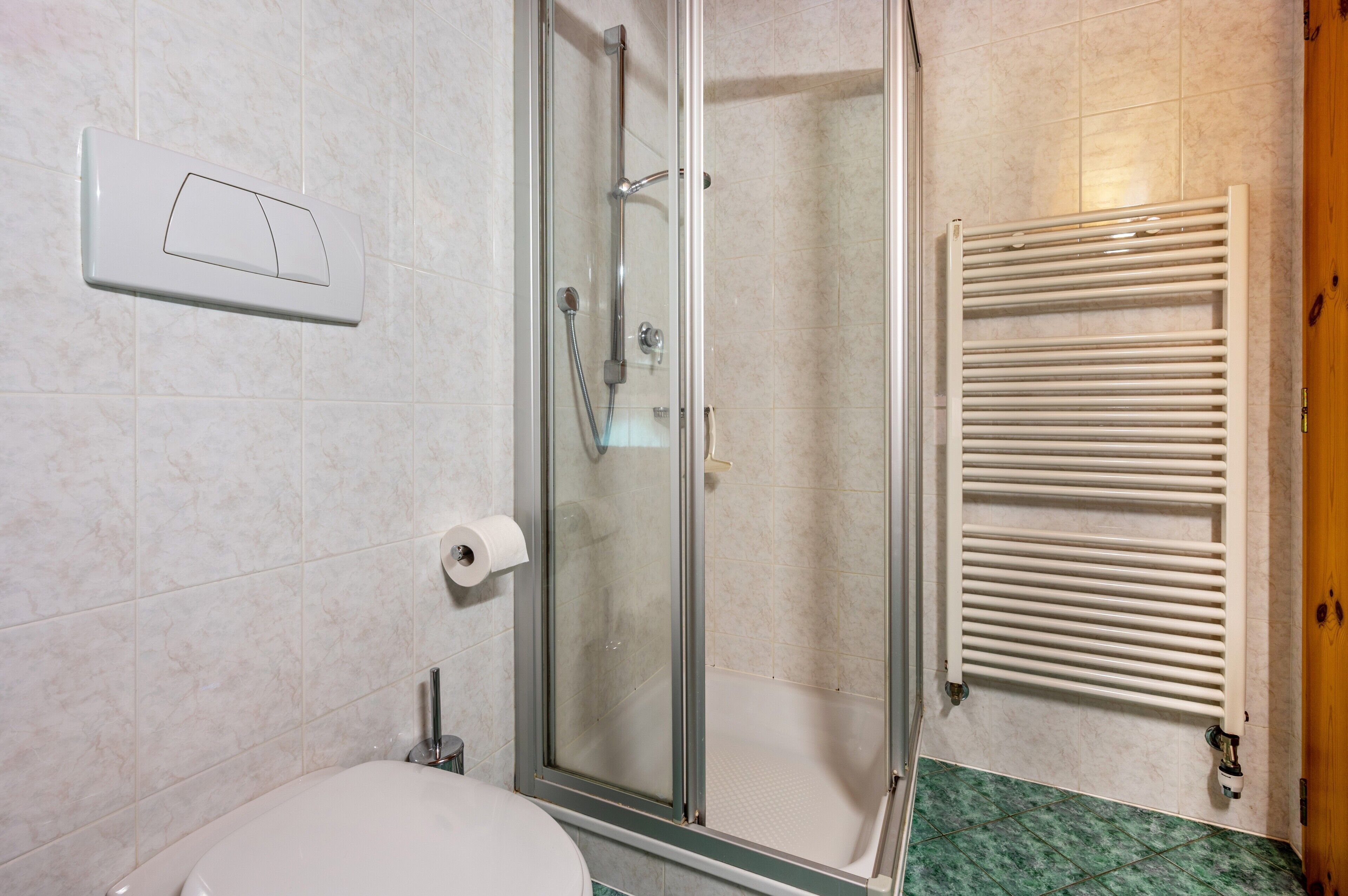 Un baño con ducha, inodoro y perchero para toallas.