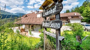 Un cartel de madera con la inscripción 'Lindenhof' y 'Heubad Sauna', señalando un lugar.