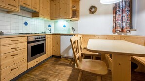 Una cocina con armarios de madera, una estufa, un fregadero y un comedor con mesa y sillas.