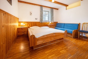 A wooden room with a bed, a blue sofa, and a chair.