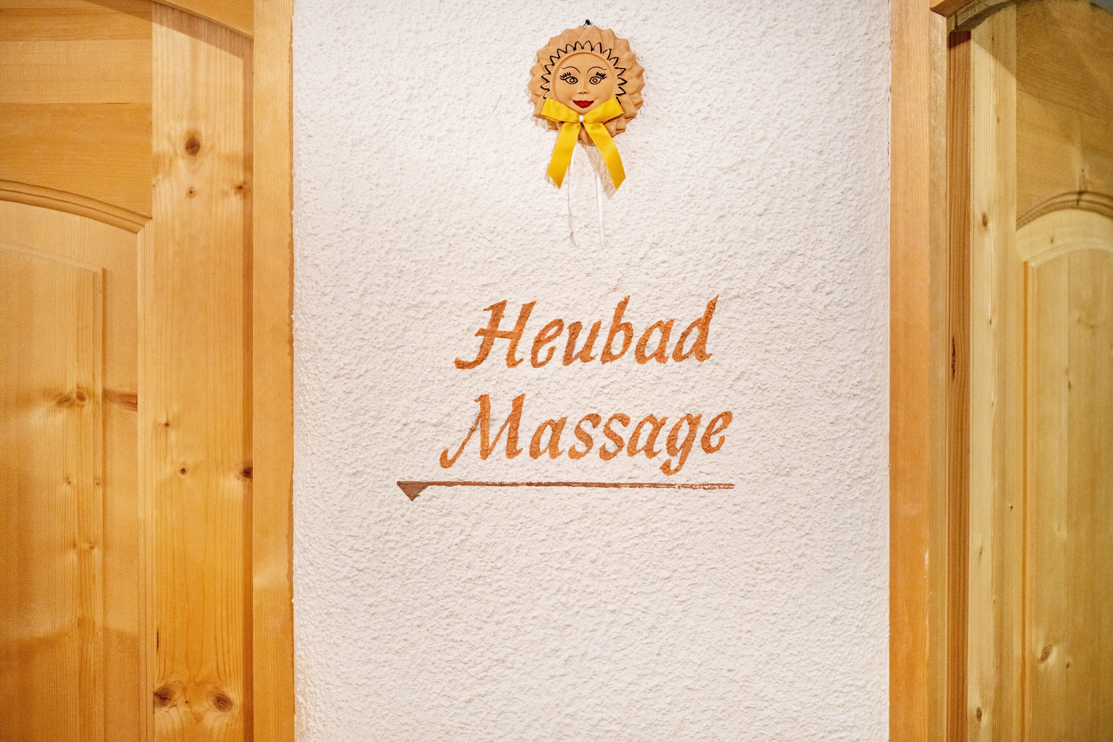 Eine Holztür mit einem Schild, auf dem 'Heubad Massage' steht.