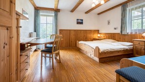 Una habitación de madera con una cama, un escritorio, una silla y una ventana.