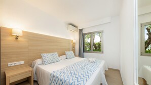 Un dormitorio con cama, lámparas de noche, mesita de noche, ventana con vistas y aire acondicionado instalado en la pared.