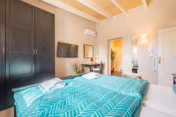 A bedroom with a bed, a dark wardrobe, a desk with a chair, a mirror, and a small table with a plant. - Country House 'Sun Club Home' with Mountain View, Wi-Fi and Air Conditioning (Llucmajor)