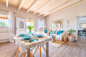 A spacious living area with a wooden dining table, white sofas, and a large mirror. - Country House 'Sun Club Home' with Mountain View, Wi-Fi and Air Conditioning (Llucmajor)